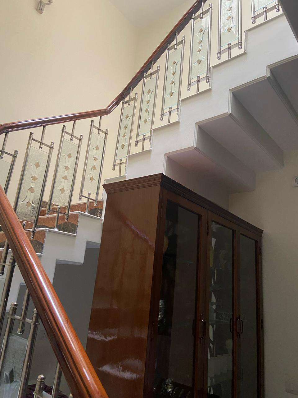A wider perspective showing the teakwood handrail integrated into the home's multi-level staircase and cabinetry design.