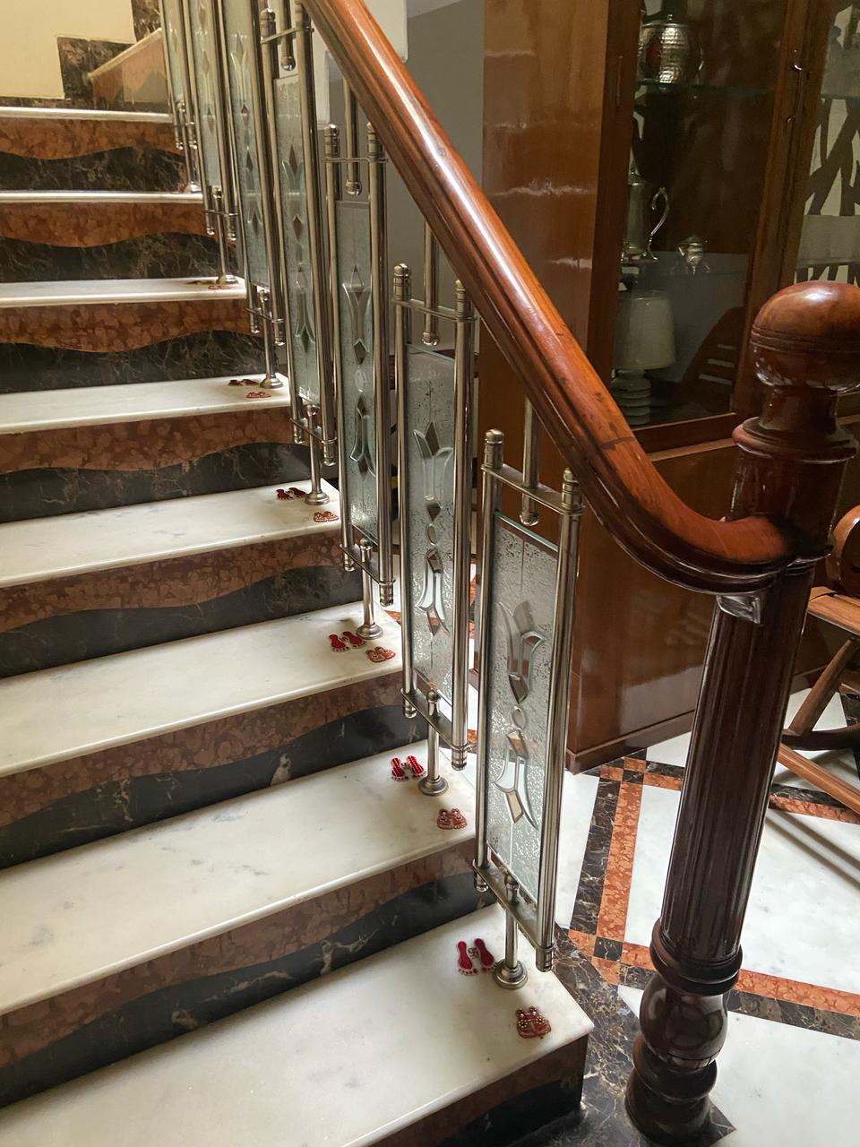 A beautifully finished wooden handrail installed on a marble staircase with glass and metal balusters.